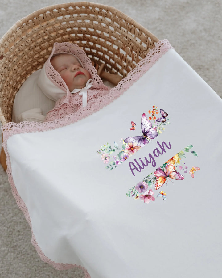 Pasgeboren meisje met een naam op een bloemen- en vlinderbedankje in een cozy mand.