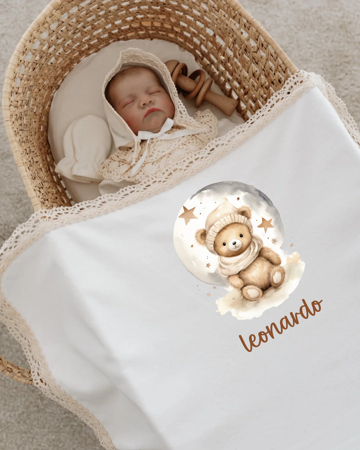 Slaapbaby in een wieg met een teddybeerprint dekentje en de naam Leonardo, omringd door gezelligheid.