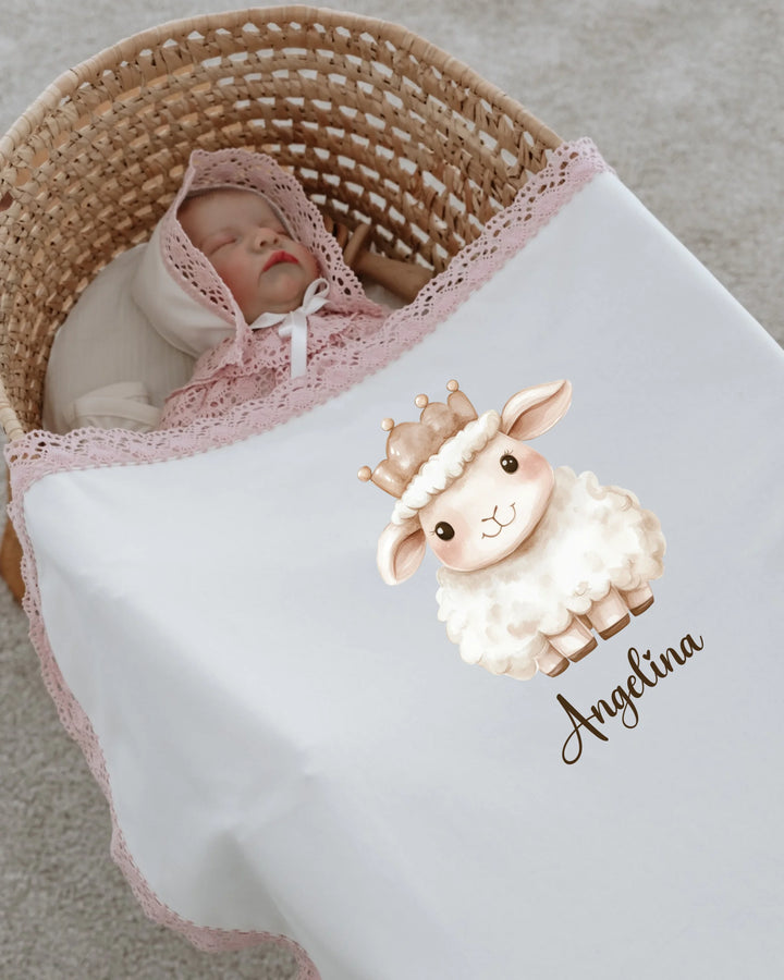 Newborn girl sleeping in a basket with a blanket featuring a cute lamb design and personalized name 'Angelina'.