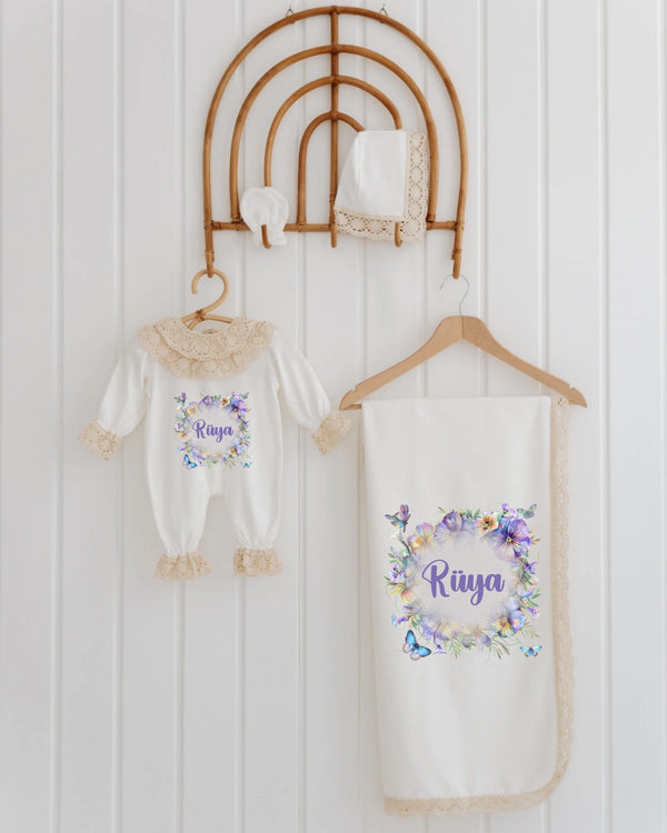 Newborn girl set with butterfly and flower design, personalized with name Raya, featuring a romper and blanket.