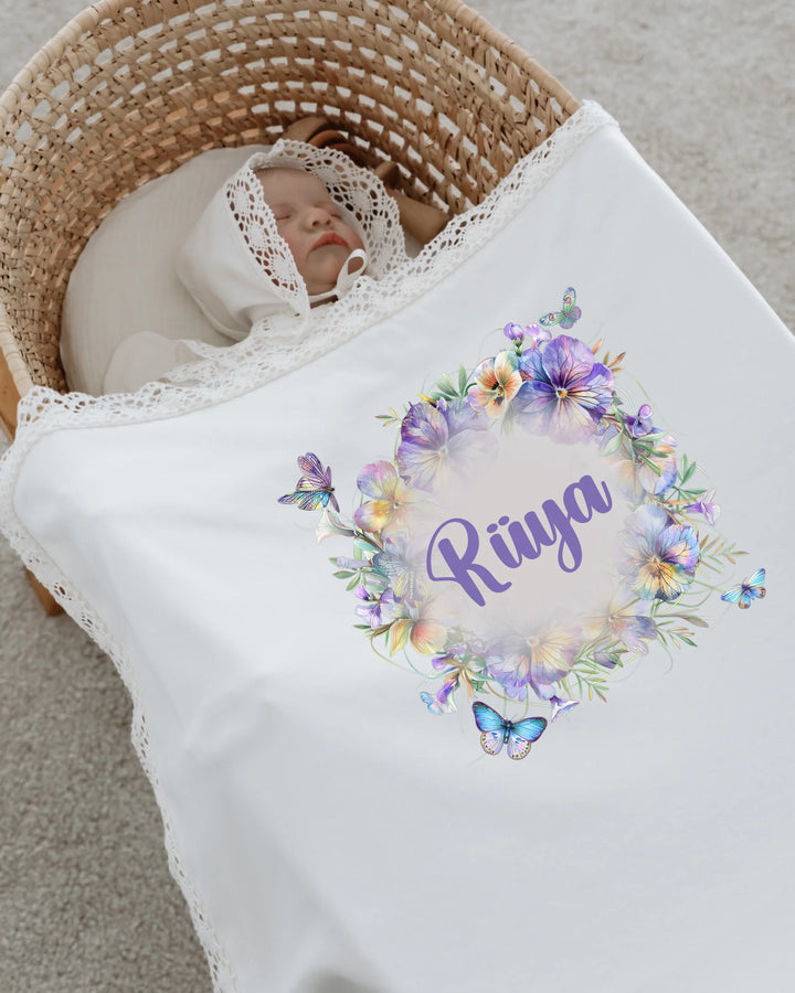 Newborn girl sleeping under a personalized floral blanket with lace trim, featuring the name 'Rüya'.