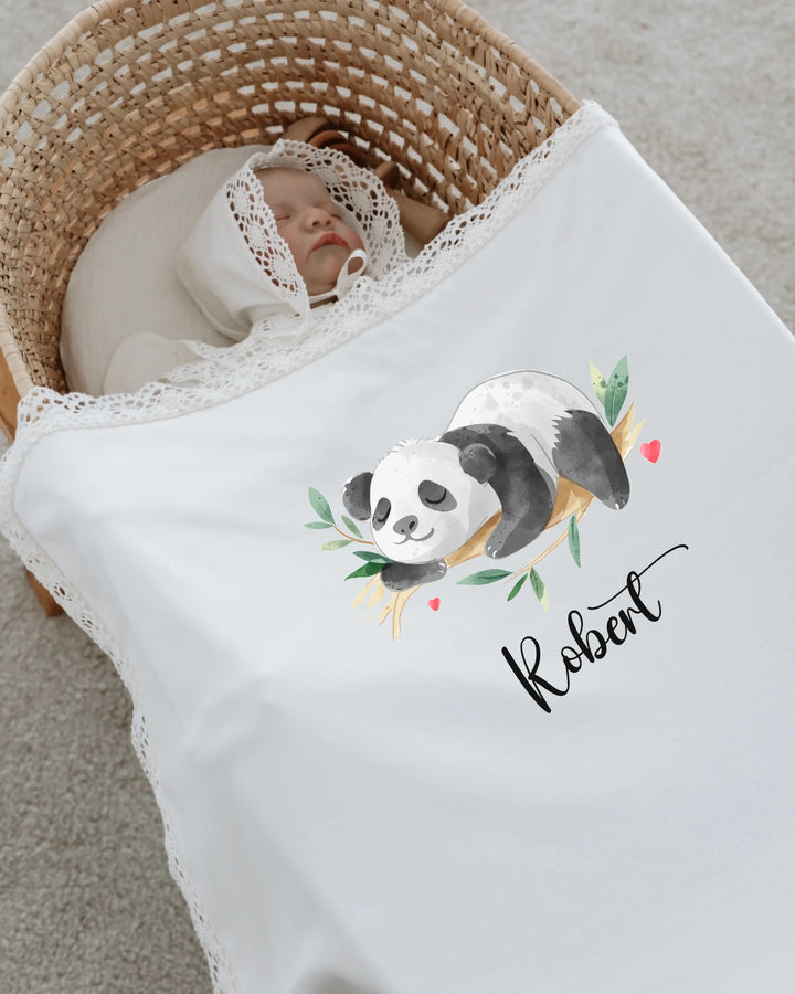 Newborn baby sleeping in a bassinet with a personalized panda blanket featuring the name Robert.
