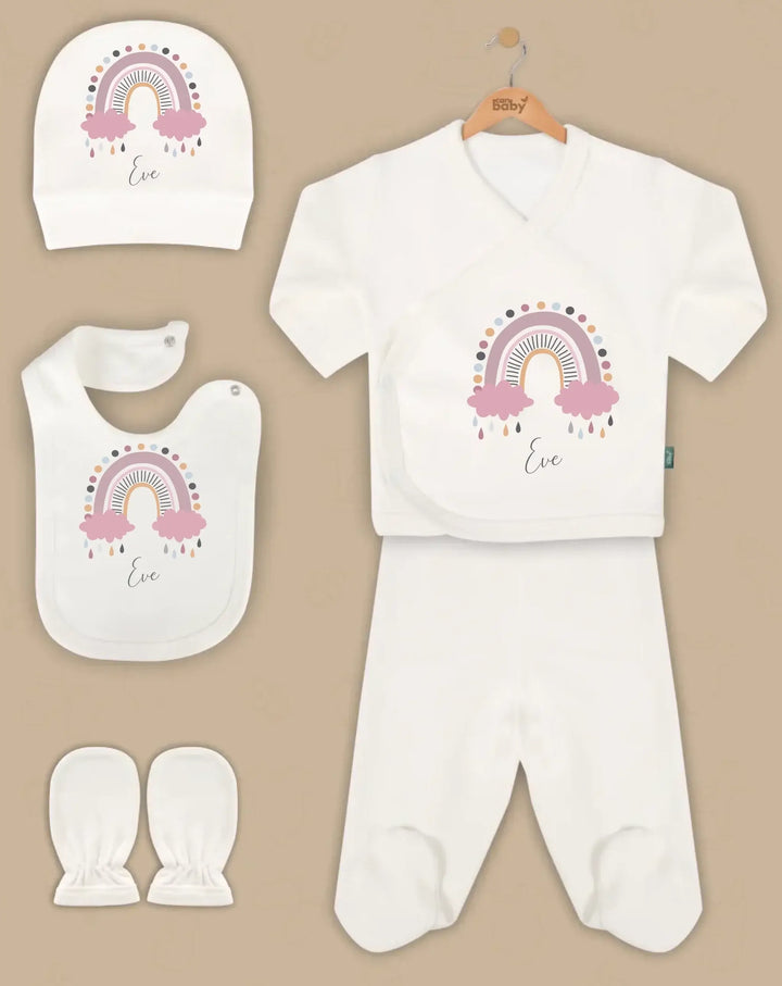 Pastel rainbow-themed personalized baby clothing gift set with hat, bib, romper, pants, and mittens in organic cotton.