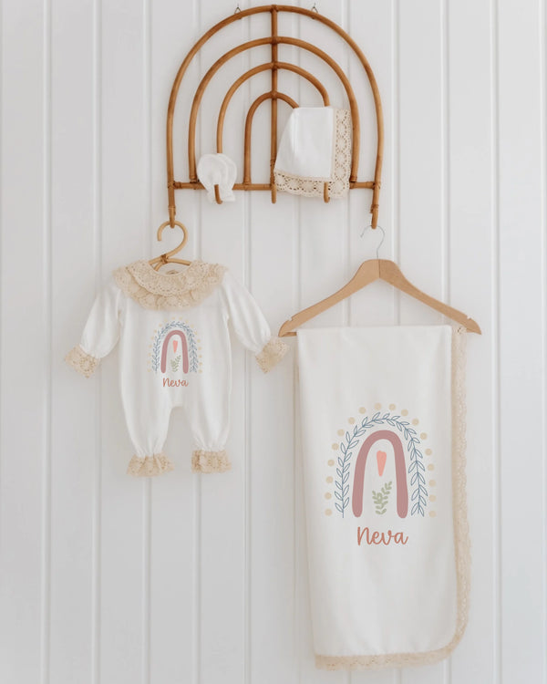 Gepersonaliseerd geboortepakje voor meisjes met regenboogillustratie en kant, inclusief bijpassende dekentje en mutsje.