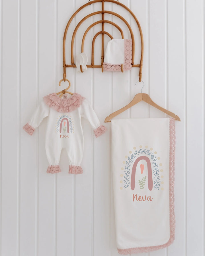 Pastel geboortepakje voor meisjes met regenboogdesign en kant, inclusief muts en dekentje, gepersonaliseerd met naam.