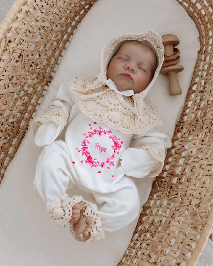 Roze newbornset voor meisjes met kant en bloemenprint, gepersonaliseerd met naam, schattige baby in een wieg.