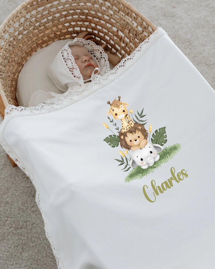 Newborn baby swaddled in a blanket featuring cute safari animals and personalized name Charles.