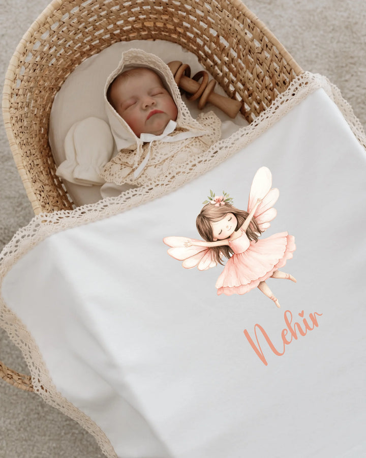 Newborn baby sleeping in a basket with a personalized fairy print blanket and bonnet.