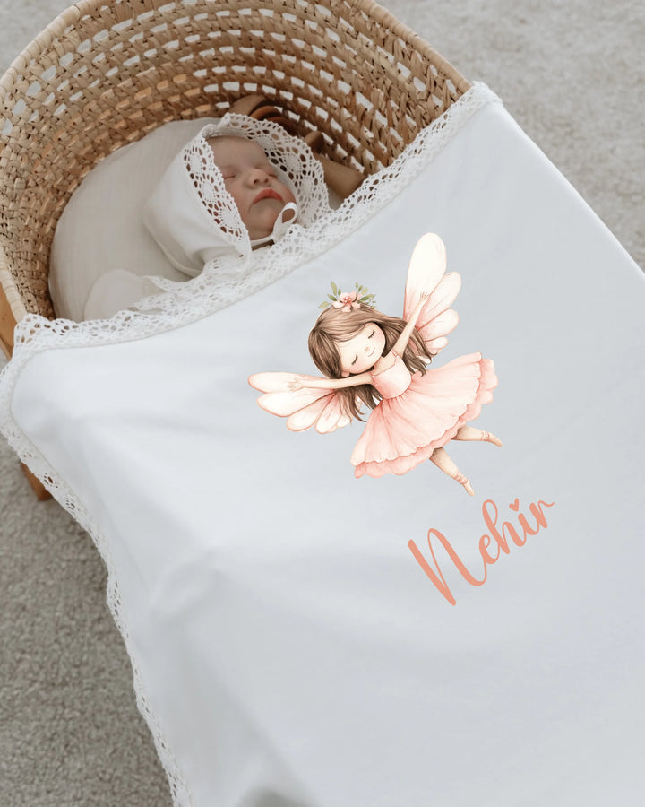 Sprookjesachtig newborn meisje in een wieg, gewikkeld in een dekentje met feeënprint en gepersonaliseerde naam.