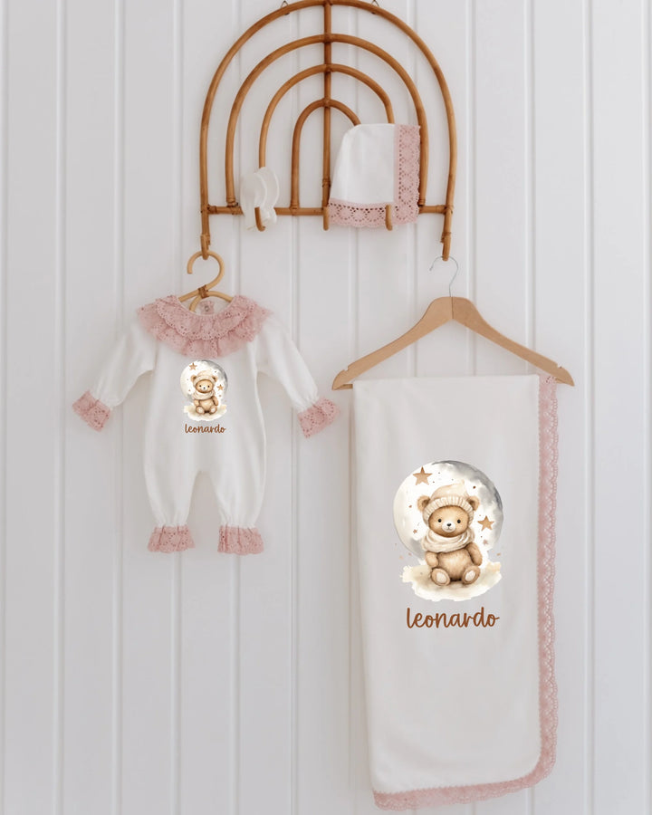 Newborn girl clothing set with teddy bear details, featuring romper, blanket, and hat in soft beige and pink.