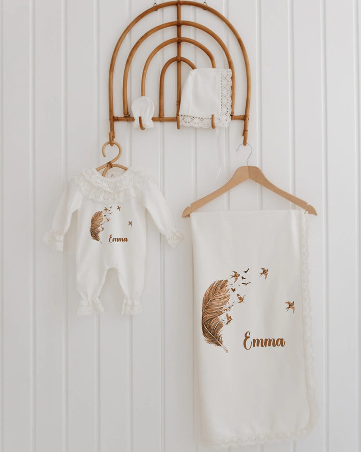 Veer & Vogels newborn girl outfit set with feather design, customized for Emma, featuring a romper, blanket, and accessories.