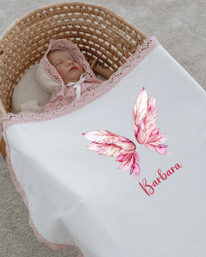Newborn girl wrapped in soft blanket with pink wings design and personalized name 'Barbara', perfect for baby photoshoots.