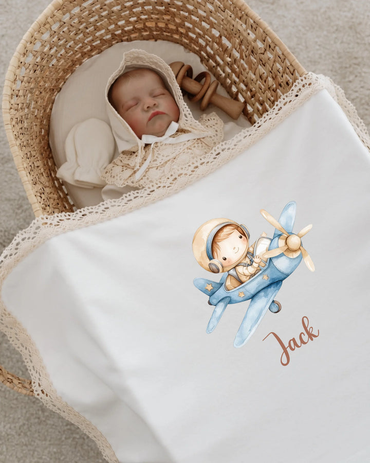 Newborn baby Jack sleeping in a basket with a personalized airplane blanket featuring a cute pilot design.