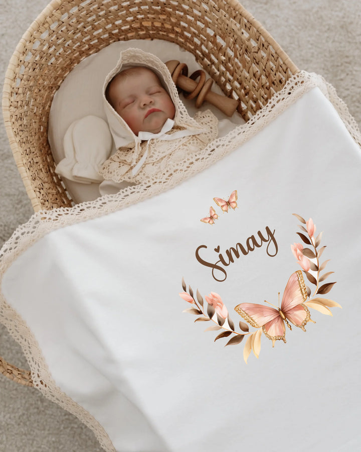 Slaapbaby in een wieg met een deken met naam en een elegante vlinderkrans, perfect voor een persoonlijk babycadeau.